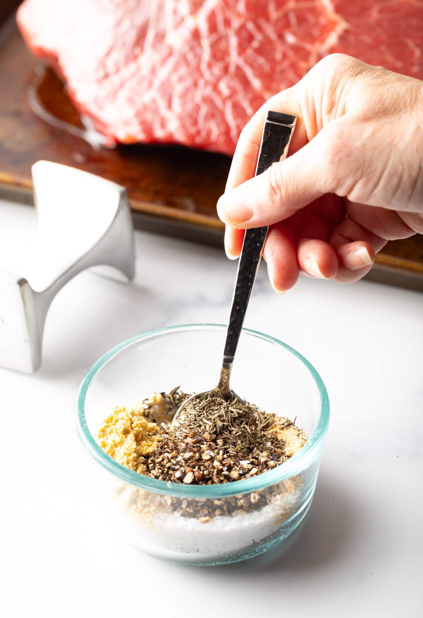 Hand stirring seasoning mix together in a small glass bowl.