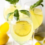 3 wine glasses each with limoncello spritz, fresh slices of lemon, and fresh mint leaves.