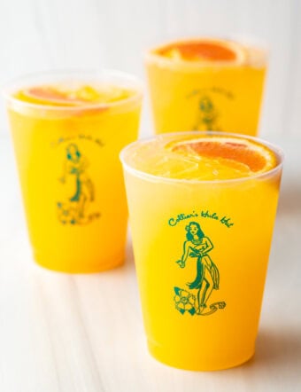 3 sunny d vodka seltzer drinks, each in a glass cup with slice of orange on top.