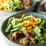 Bowl of Taiwanese beef soup with noodles, green scallions, and chopped bok choy.