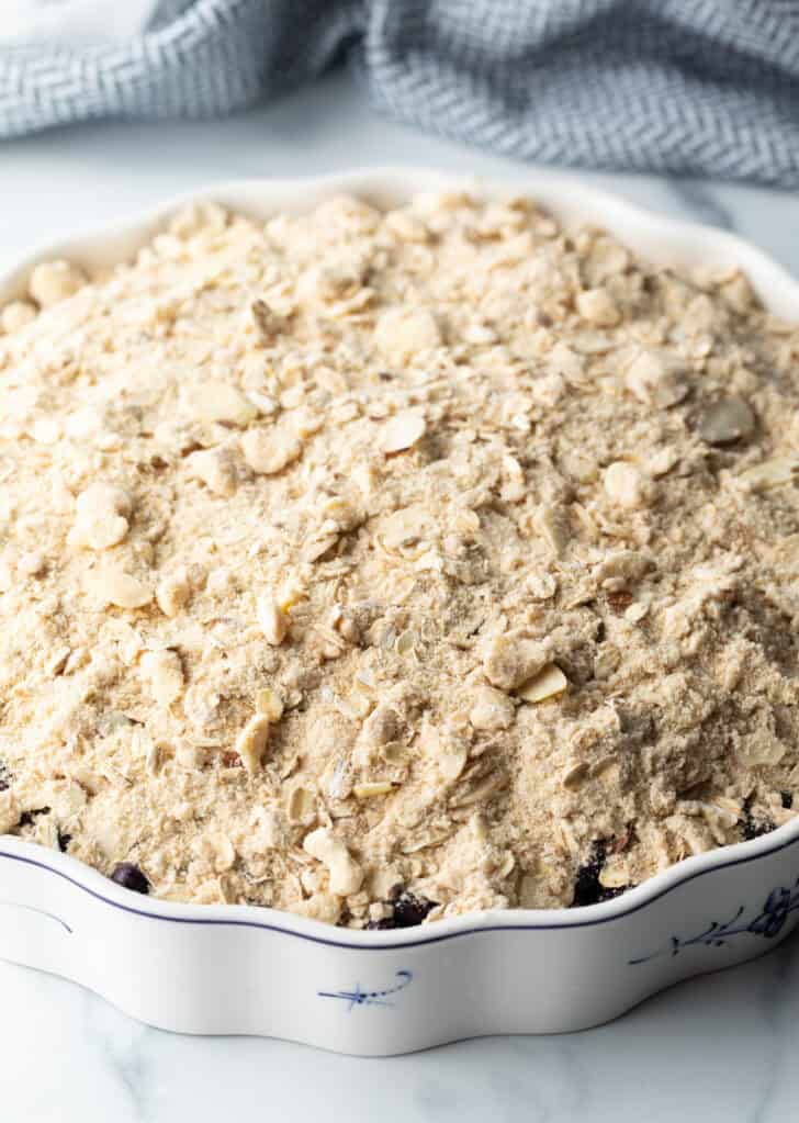 Raw crumble topping on top of the blueberries in a baking dish.