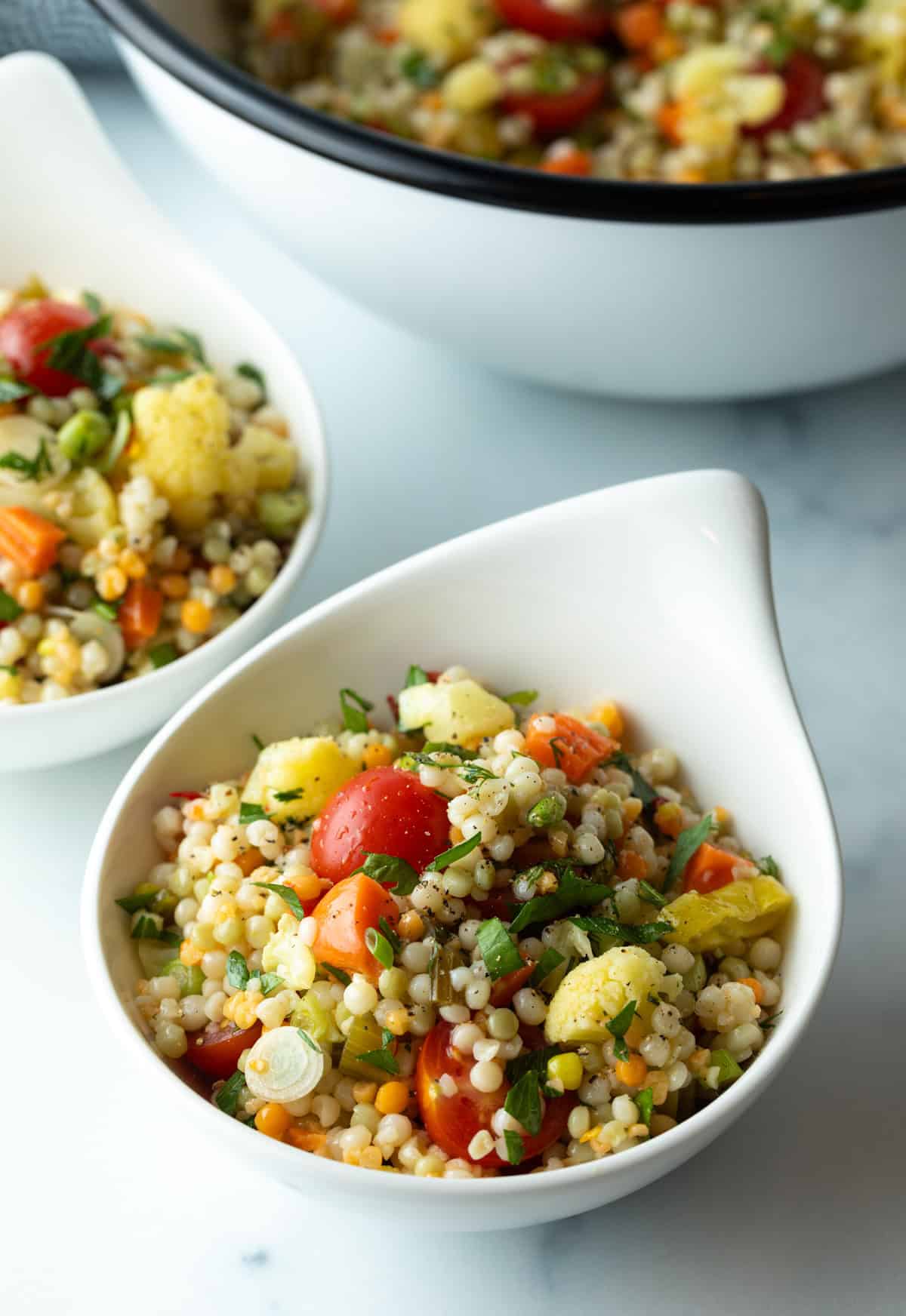 Serving of Israeli couscous salad in a white bowl.