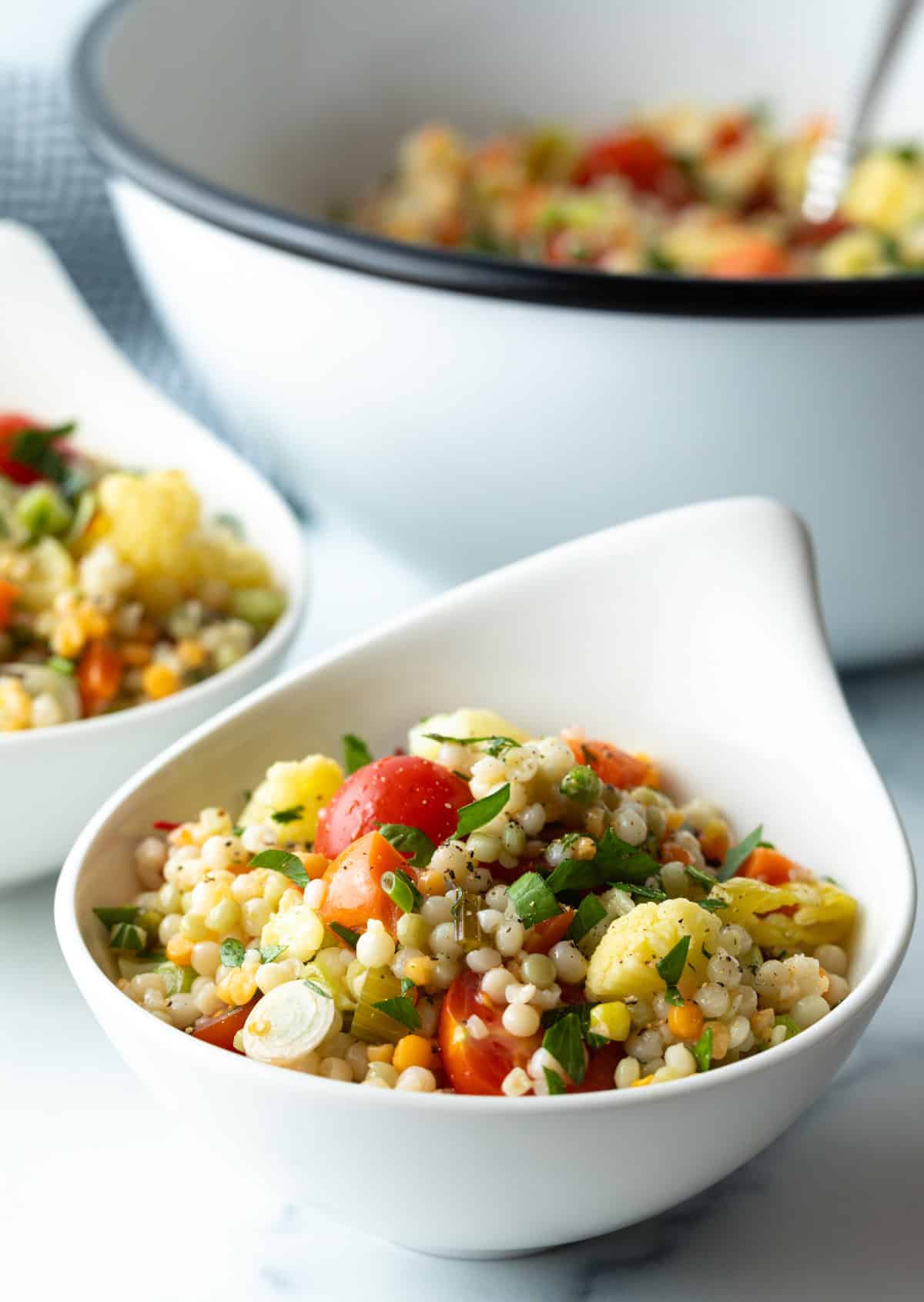 Serving of Israeli couscous salad in a white bowl.