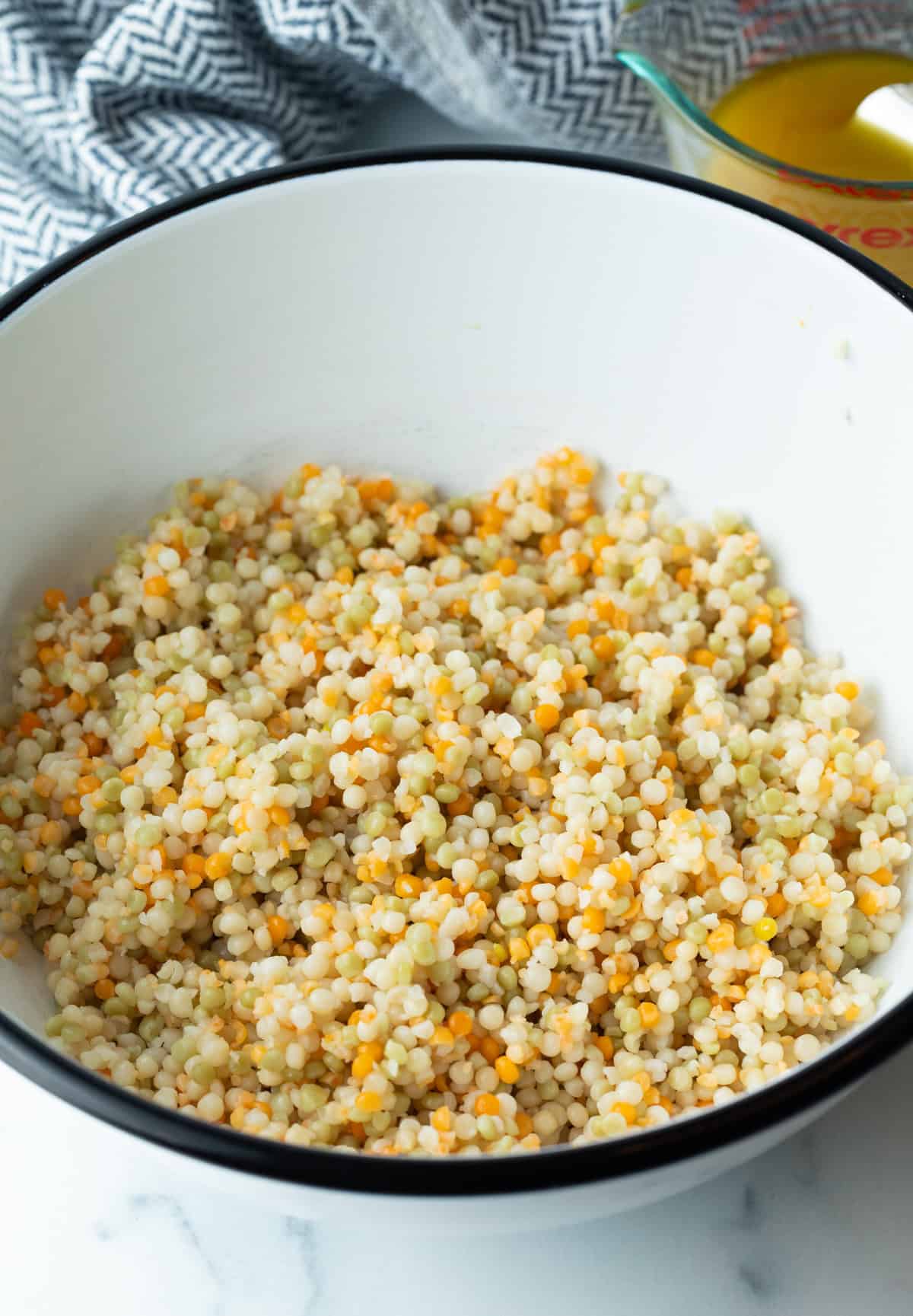 Cooked and cooled cous cous in a large mixing bowl.