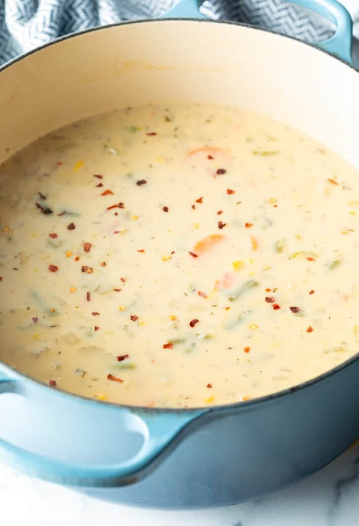 Large blue pot of creamy soup with veggies.