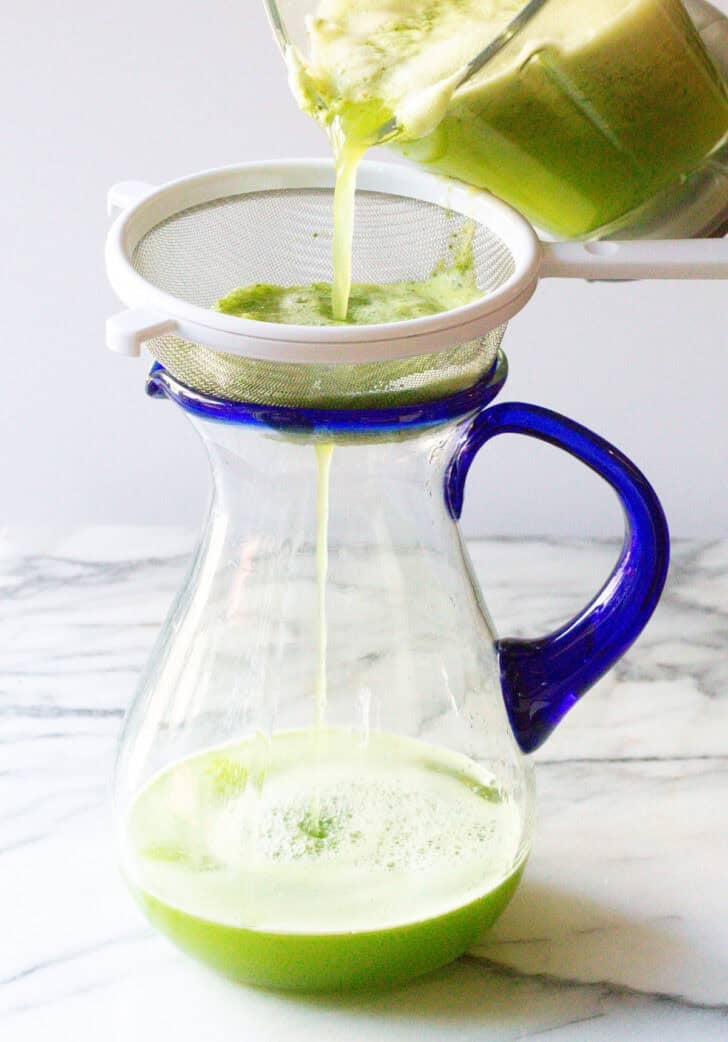 pouring pureed agua fresca through a fine mesh seive