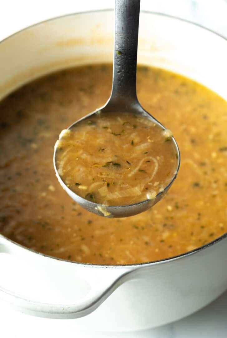 Metal ladle showing onion soup to camera.