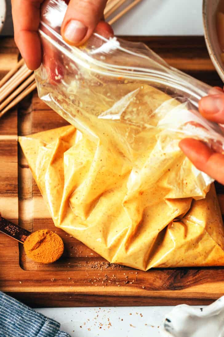 Ziploc bag filled with satay sauce and pieces of chicken.