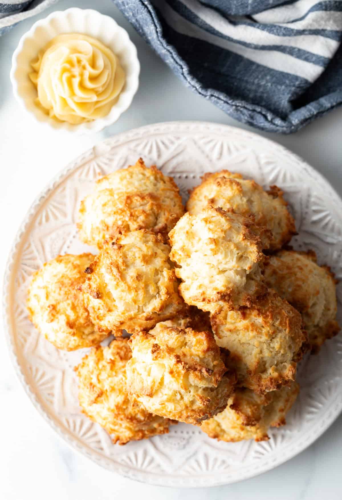 Top down view white plate with two-layer high stack of several homemade buttermilk biscuits.