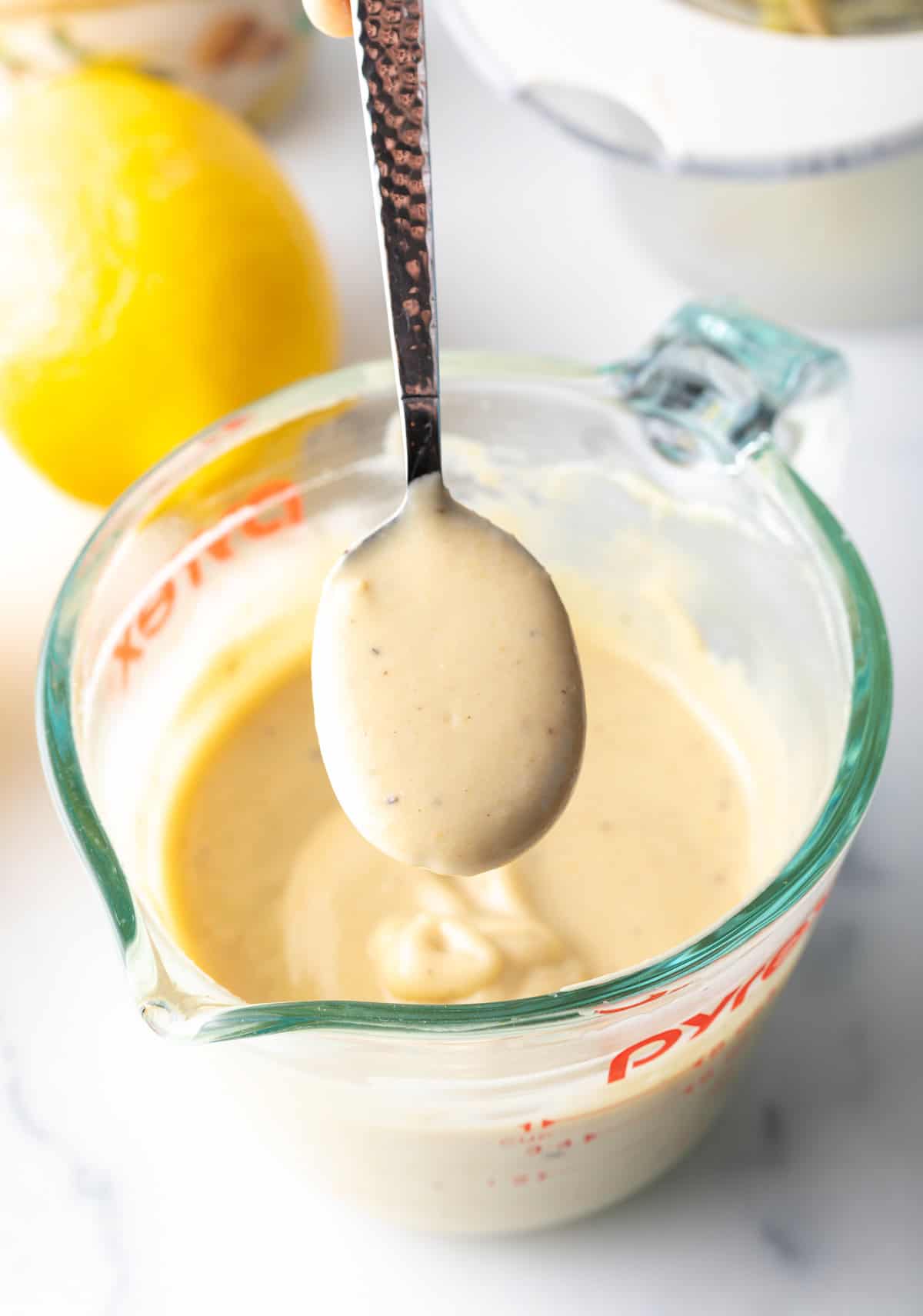 Spoon holding creamy dressing up to camera. 