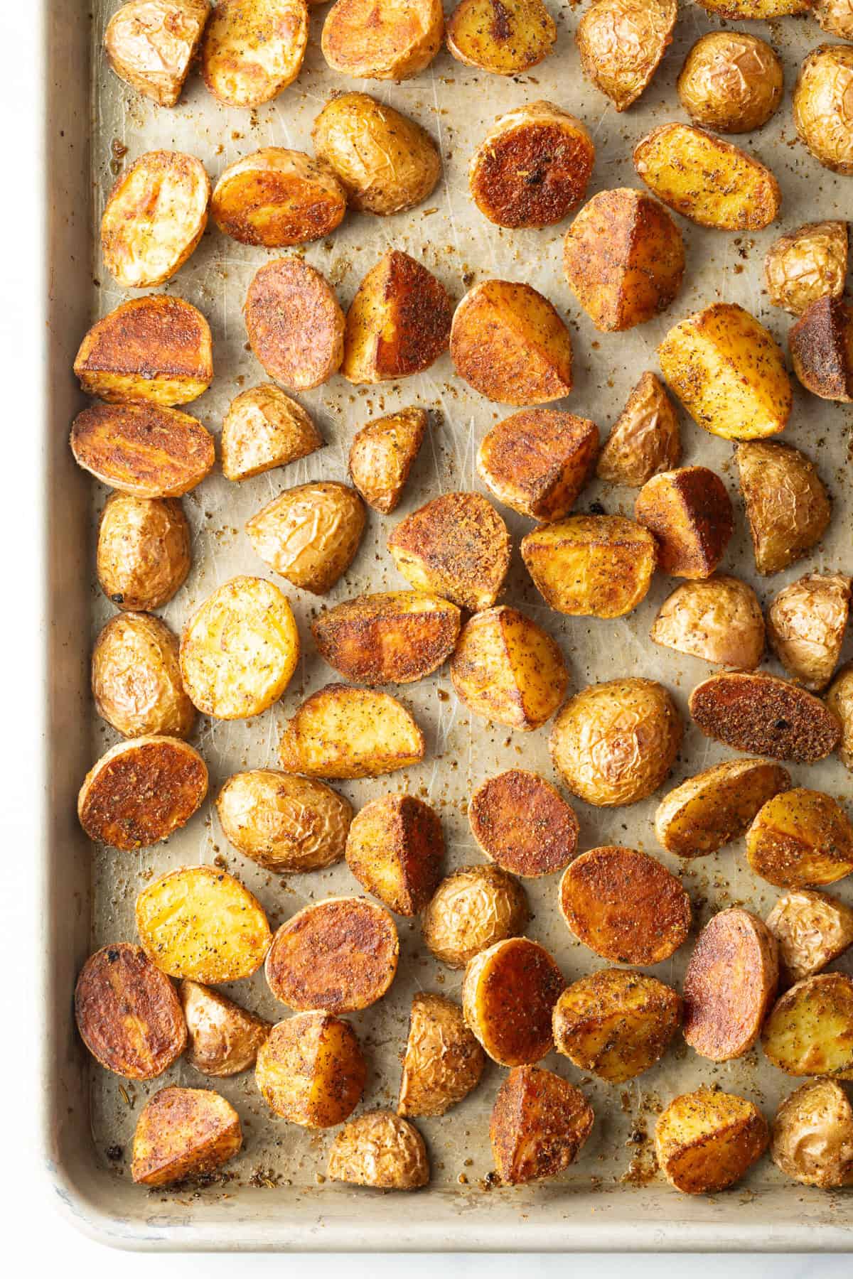 Top down view halved yellow baby potatoes roasted on a baking sheet.