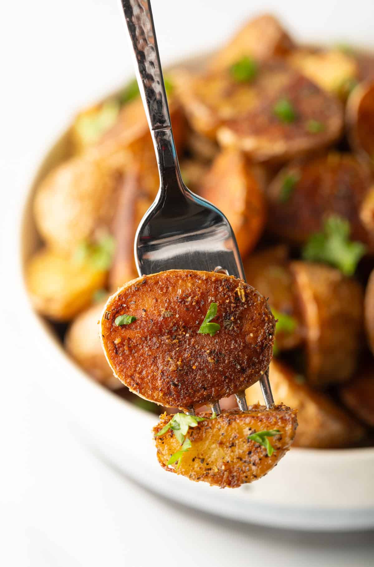 Fork showing a crispy potato piece to camera.