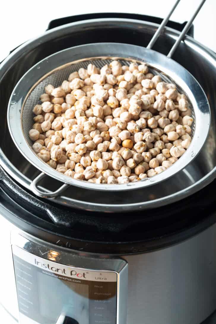 Sieve full of garbanzo beans sitting on top of and instant pot.