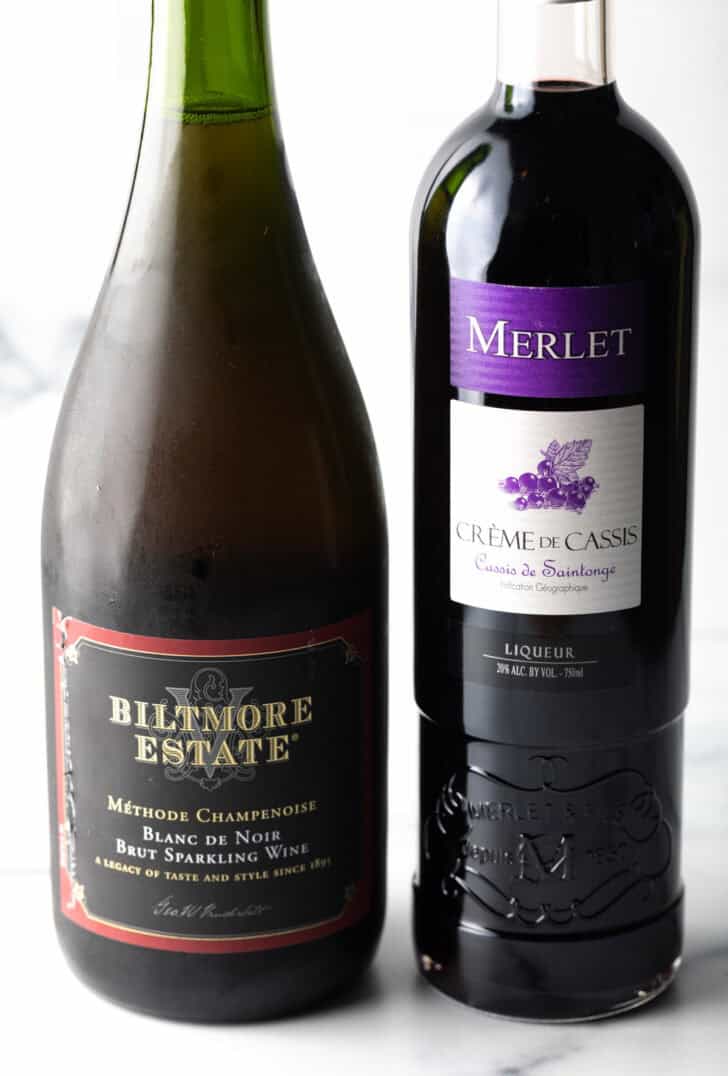 A bottle of champagne and bottle of creme de cassis.