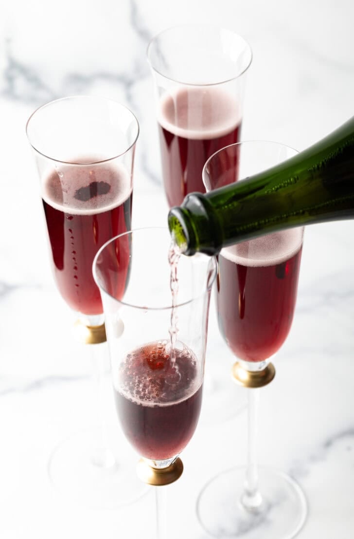 Pouring champagne into a fluted glass with red creme de cassis.
