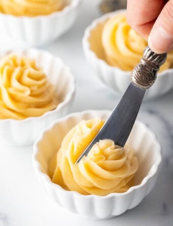 Butter knife cutting into a swirl of whipped honey butter in a ramekin.