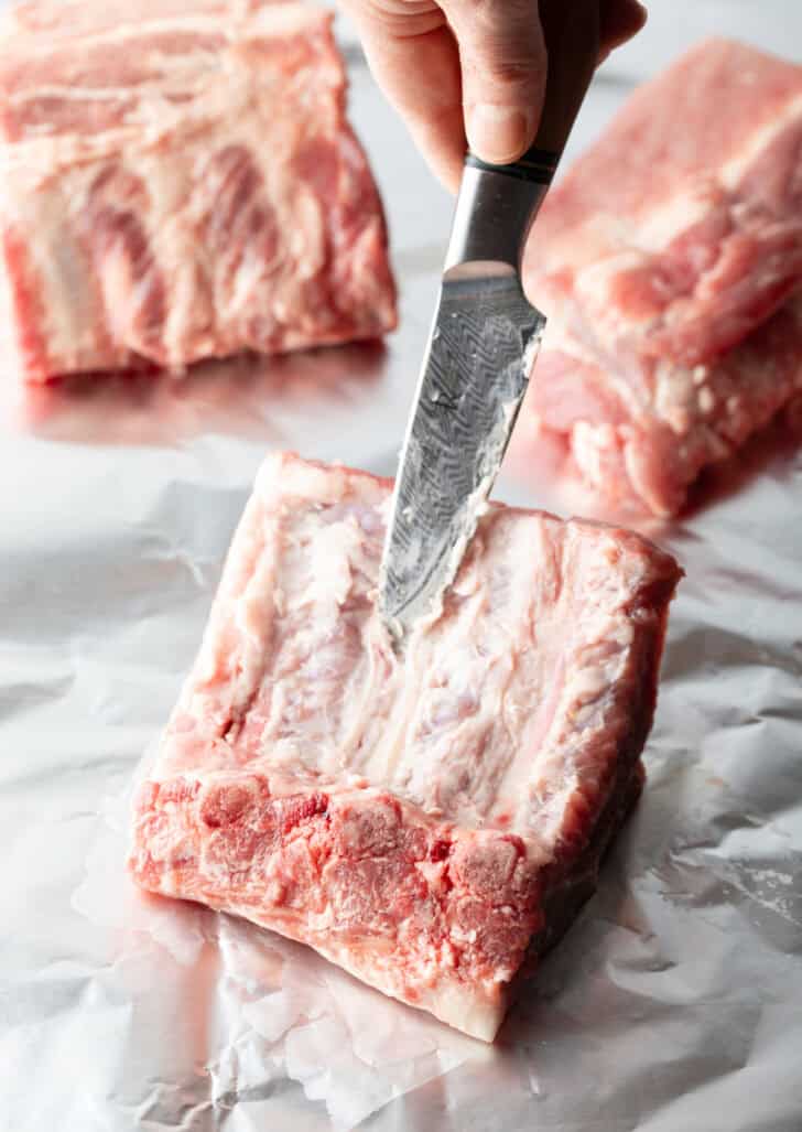 Cutting a rack of 4 baby back ribs into individual ribs.
