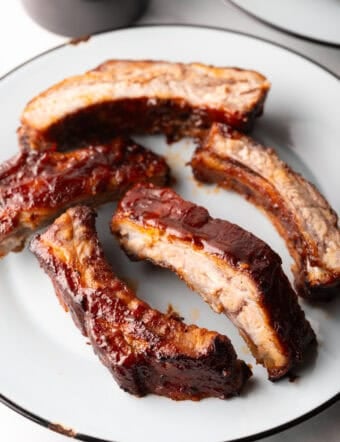 5 air fried baby back ribs on a white plate.