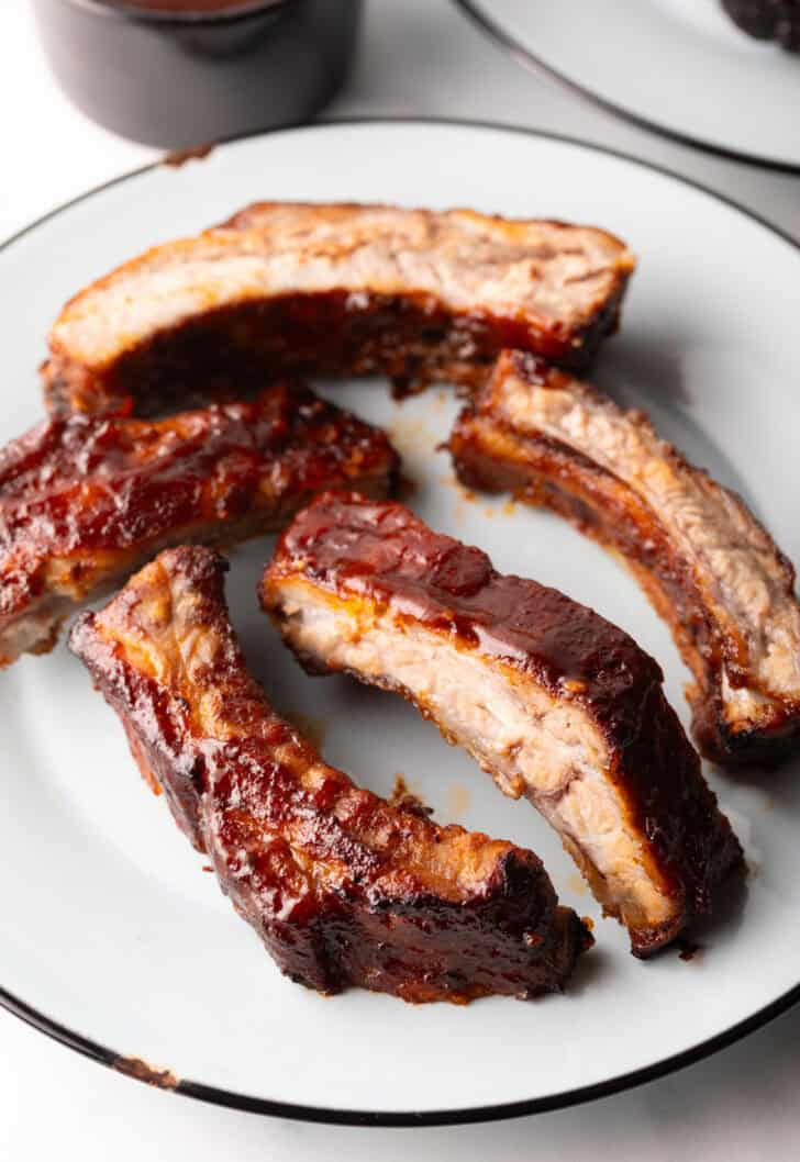5 air fried baby back ribs on a white plate.