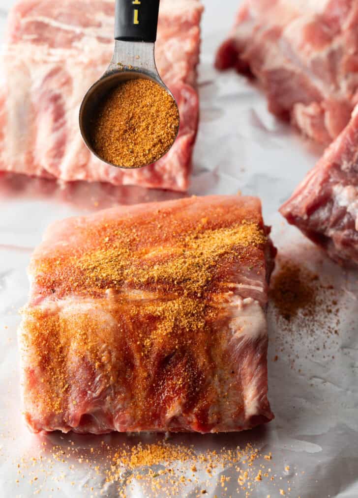 Small rack of baby back ribs coated in seasoning.