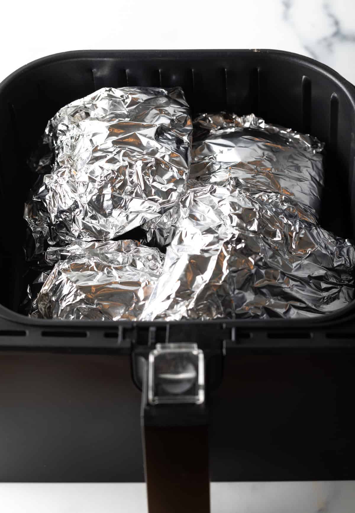Ribs wrapped in foil cooking in the air fryer.