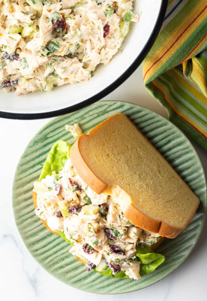 Cranberry chicken salad sandwich with top mostly open to show the salad and fresh greens inside.