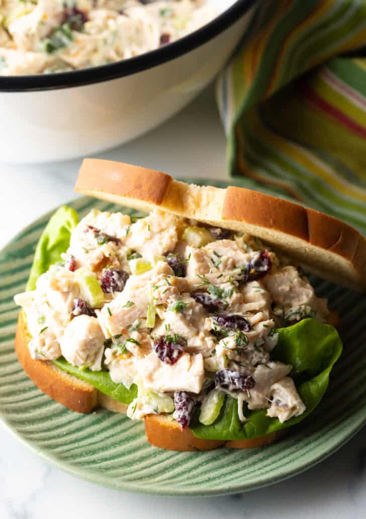 Cranberry chicken salad sandwich with top mostly open to show the salad and fresh greens inside.