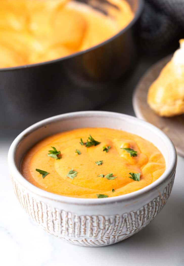 White bowl with creamy red tomato gravy topped with fresh chopped parsley.