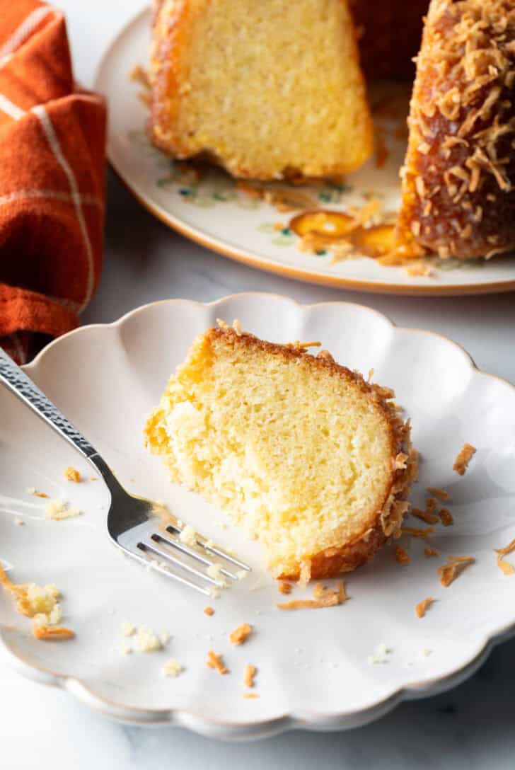 Slice of rum cake on a white plate with a fork.