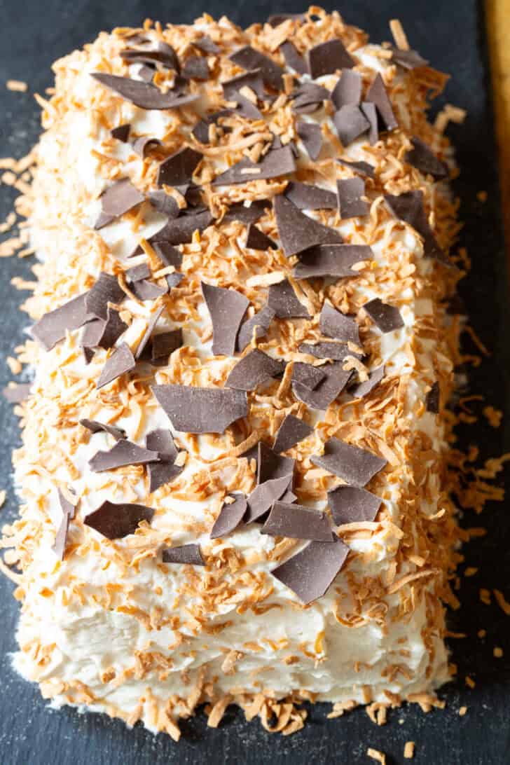 Rectangle ice box cake topped with toasted coconut and chocolate shavings.