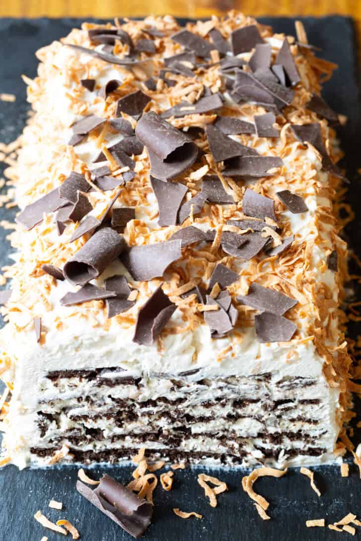 Icebox cake with layers of chocolate graham crackers, whipped cream, Kahlua and topped with toasted coconut and chocolate shavings.