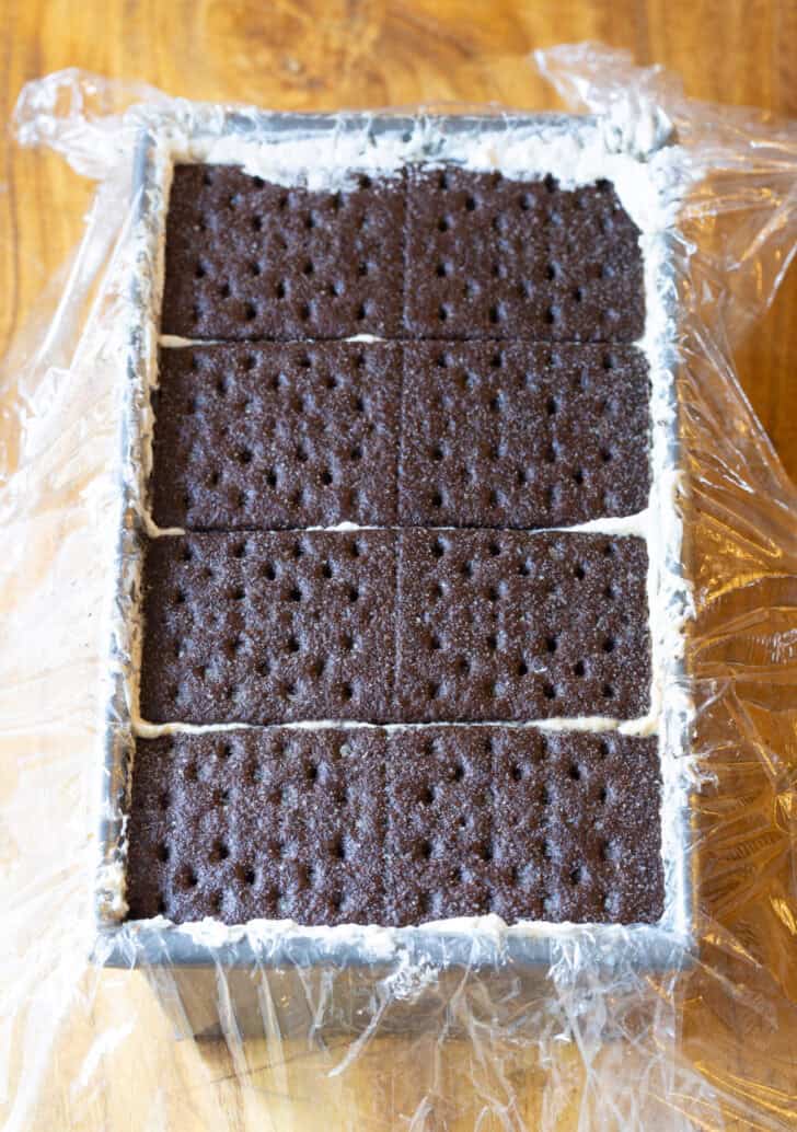 Layering chocolate graham crackers in a rectangle baking pan.