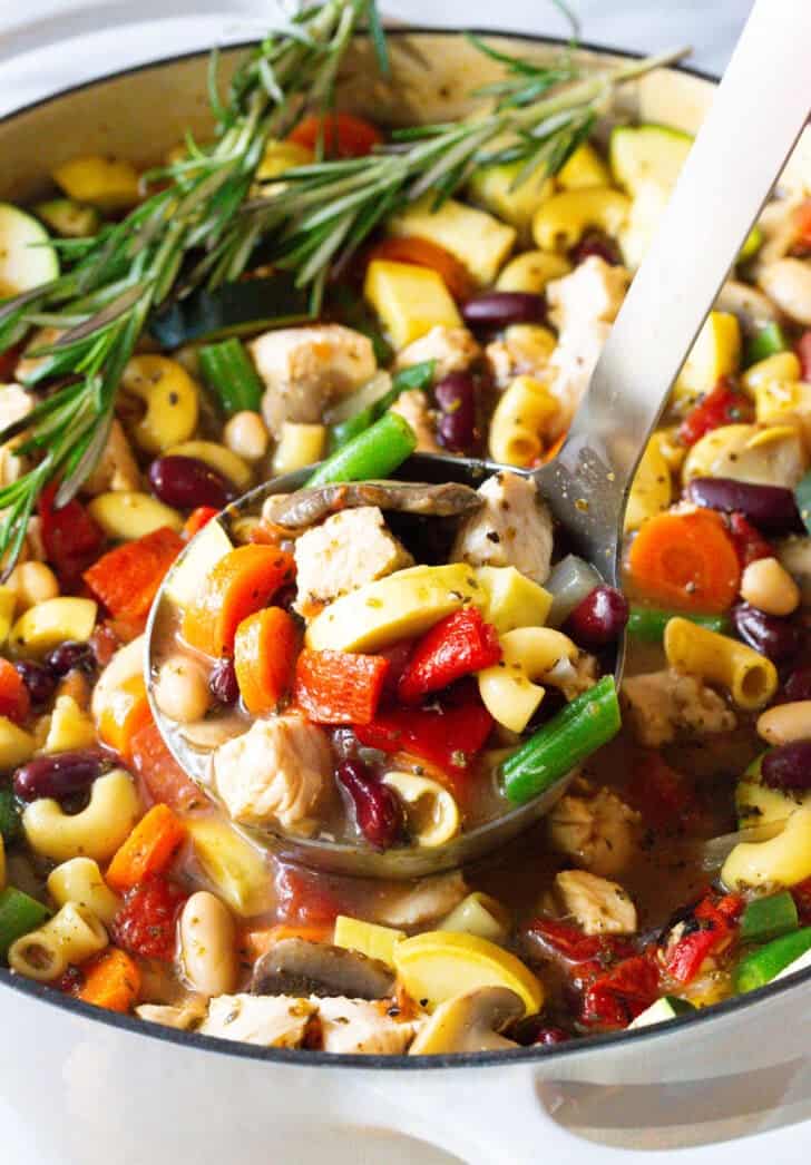 Ladleful of chicken and vegetable minestrone soup.
