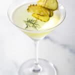 A martini glass with dill pickle juice and gin, garnished with pickle slices.