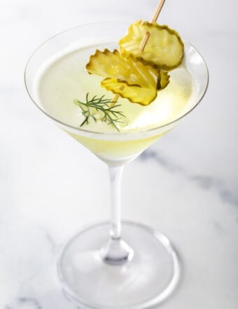 A martini glass with dill pickle juice and gin, garnished with pickle slices.
