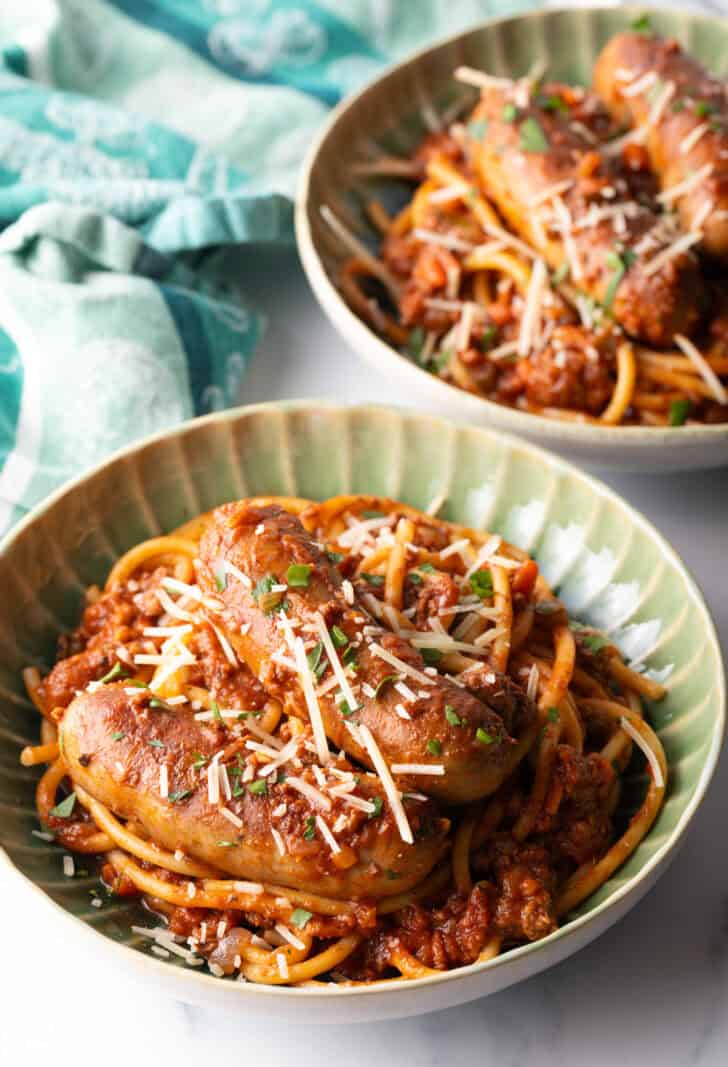 Green bowl with Sunday gravy pasta with meat sauce and sausages.