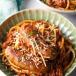 Green bowl with Sunday gravy pasta with meat sauce and sausages.