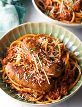 Green bowl with Sunday gravy pasta with meat sauce and sausages.