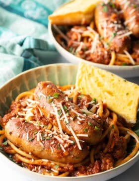 Green bowl with Sunday gravy pasta with meat sauce and sausages.