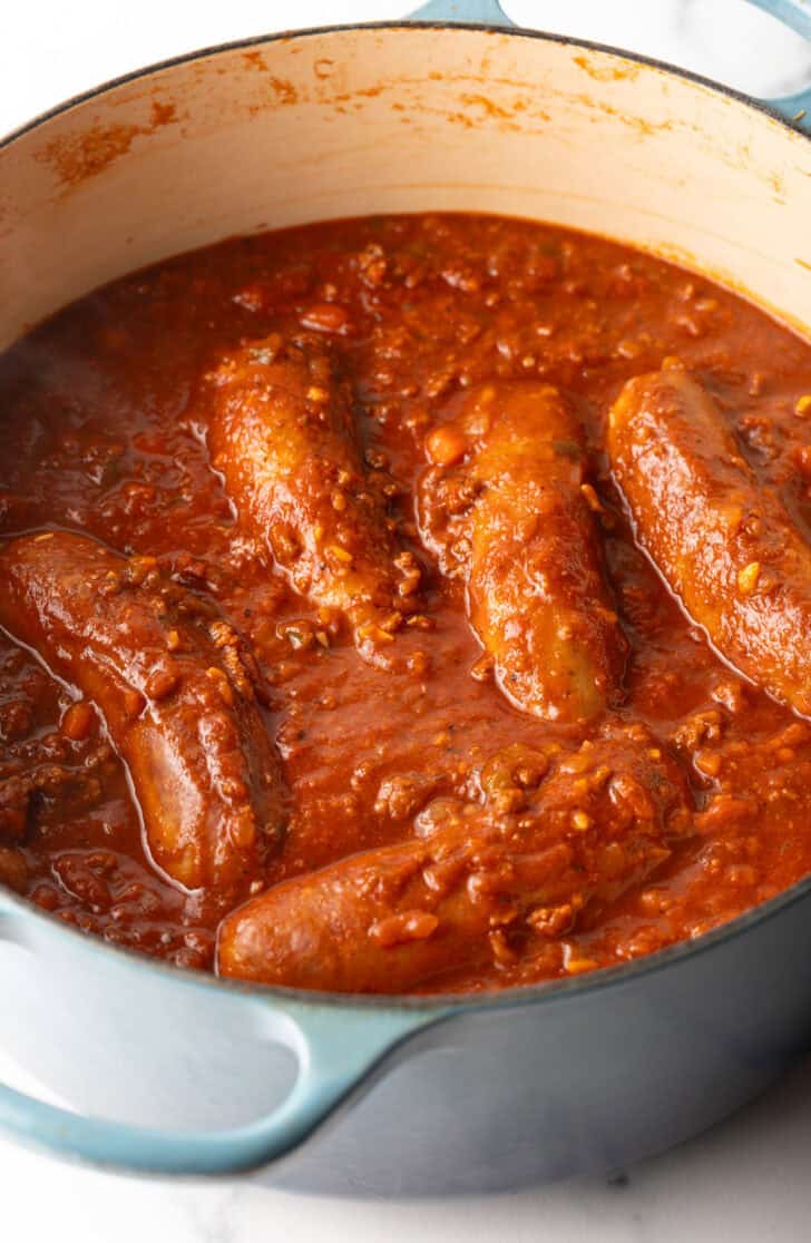 Large Italian sausages cooking in tomato sauce.