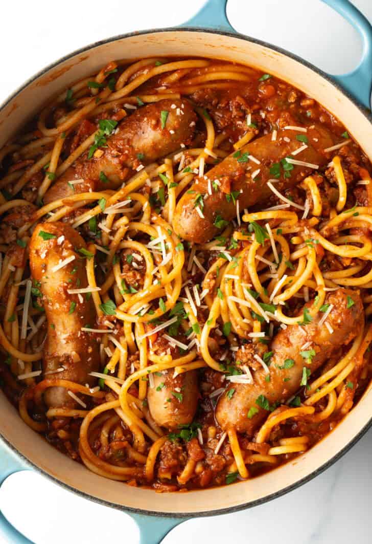 Top down one pot of spaghetti, sausage, and tomato sauce.