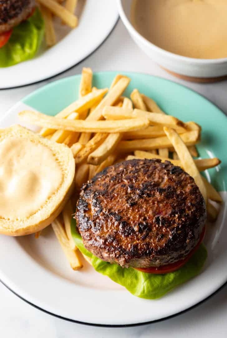 Open faced burger on a plate with fries.