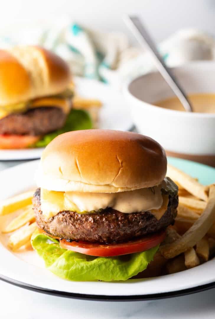 Cheeseburger on a plate surrounded by french fries.