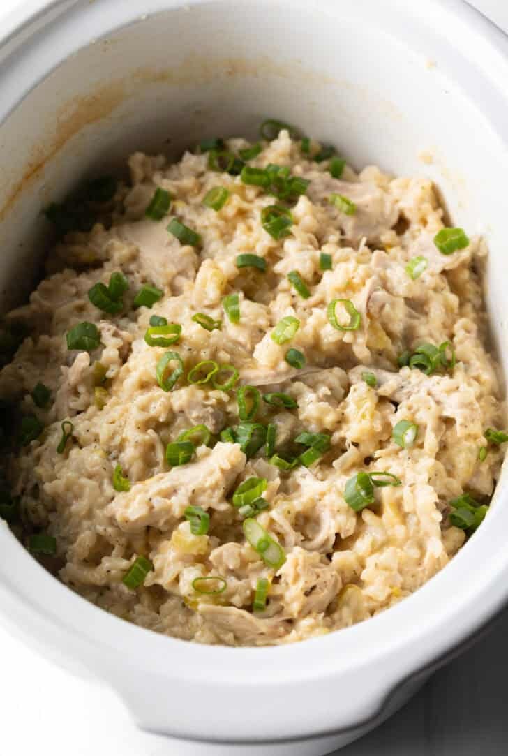 White crockpot with finished chicken and rice.