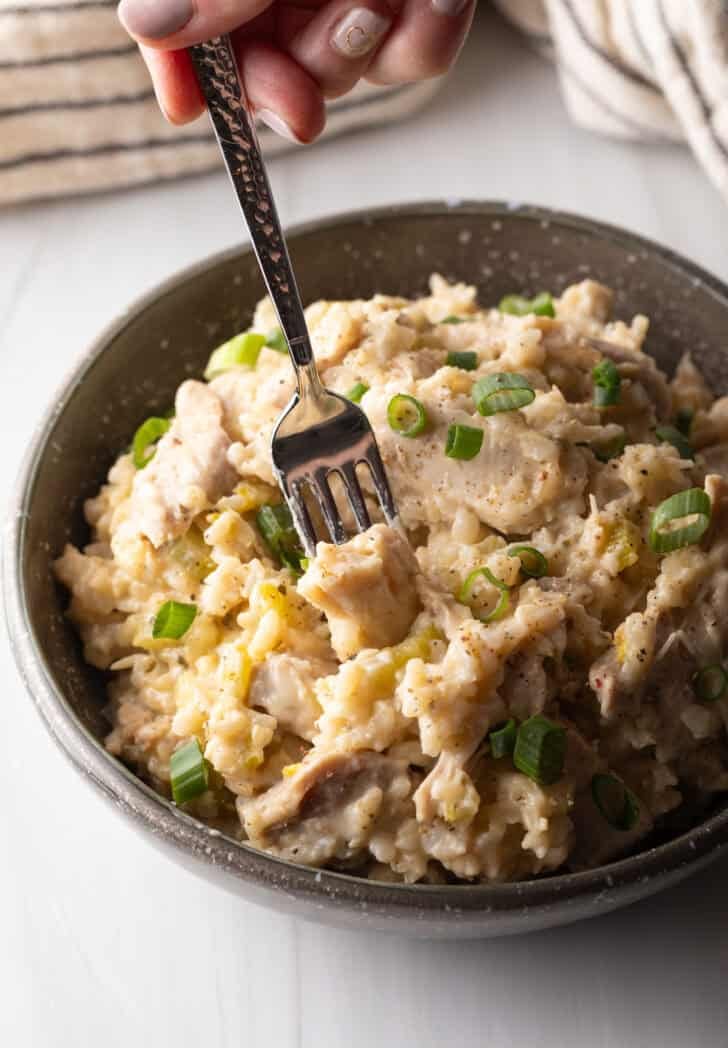 Chicken and rice in a black bowl with a fork.