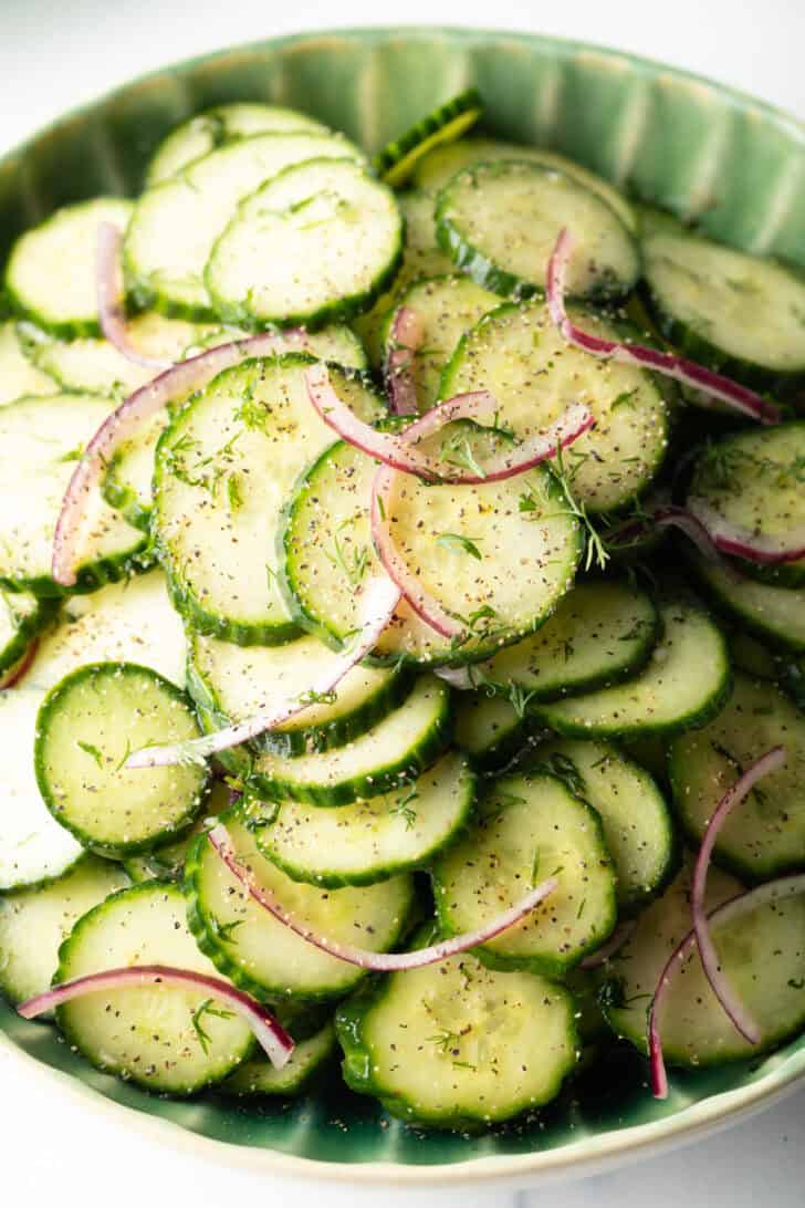 Close view of cucumber and onion salad on a green plate.
