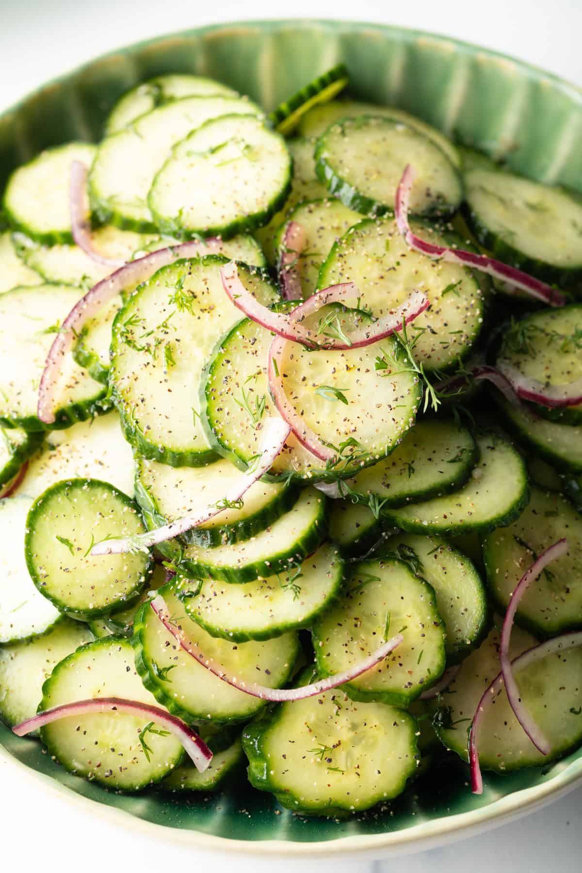Close view of cucumber and onion salad on a green plate.