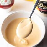 Spoon of burger sauce held over a bowl of sauce.