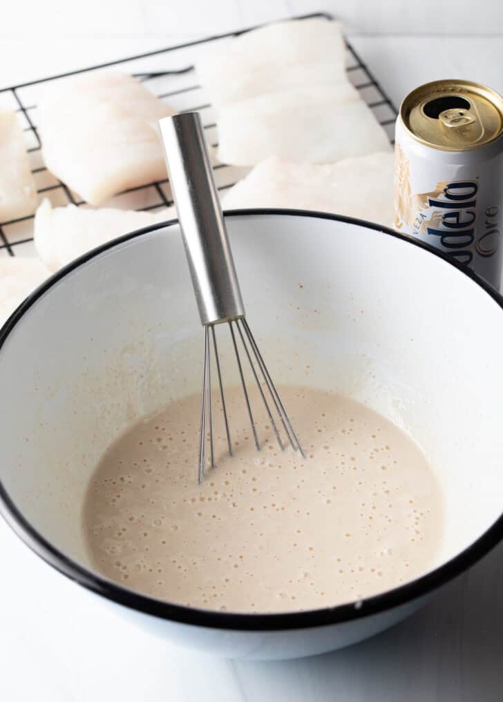 White bowl with batter and wire whisk.