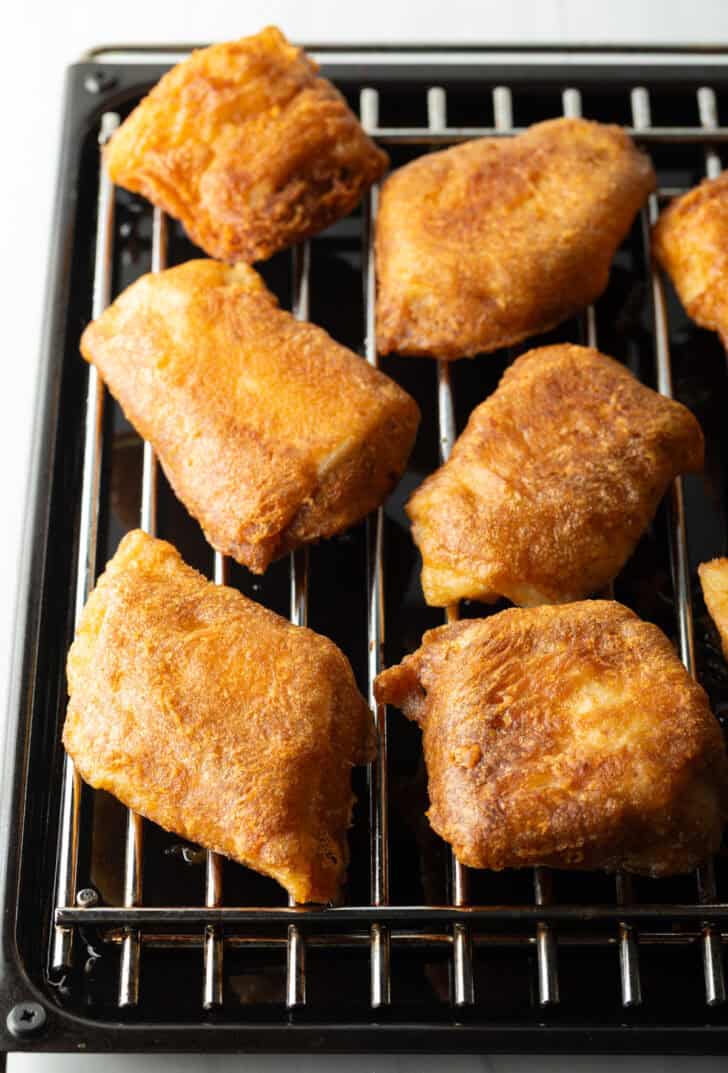 Several pieces of fried fish on a wire rack.